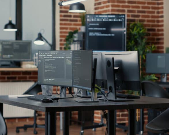 two computer monitors sitting on top of a desk